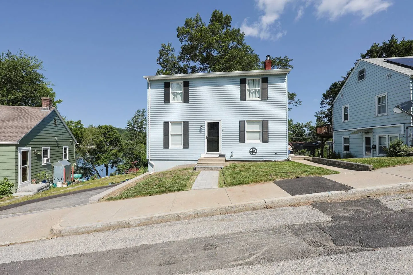 The flagship home on Indian Lake Parkway in Worcester: a light blue two-story house with black shutters, with the lake behind it.