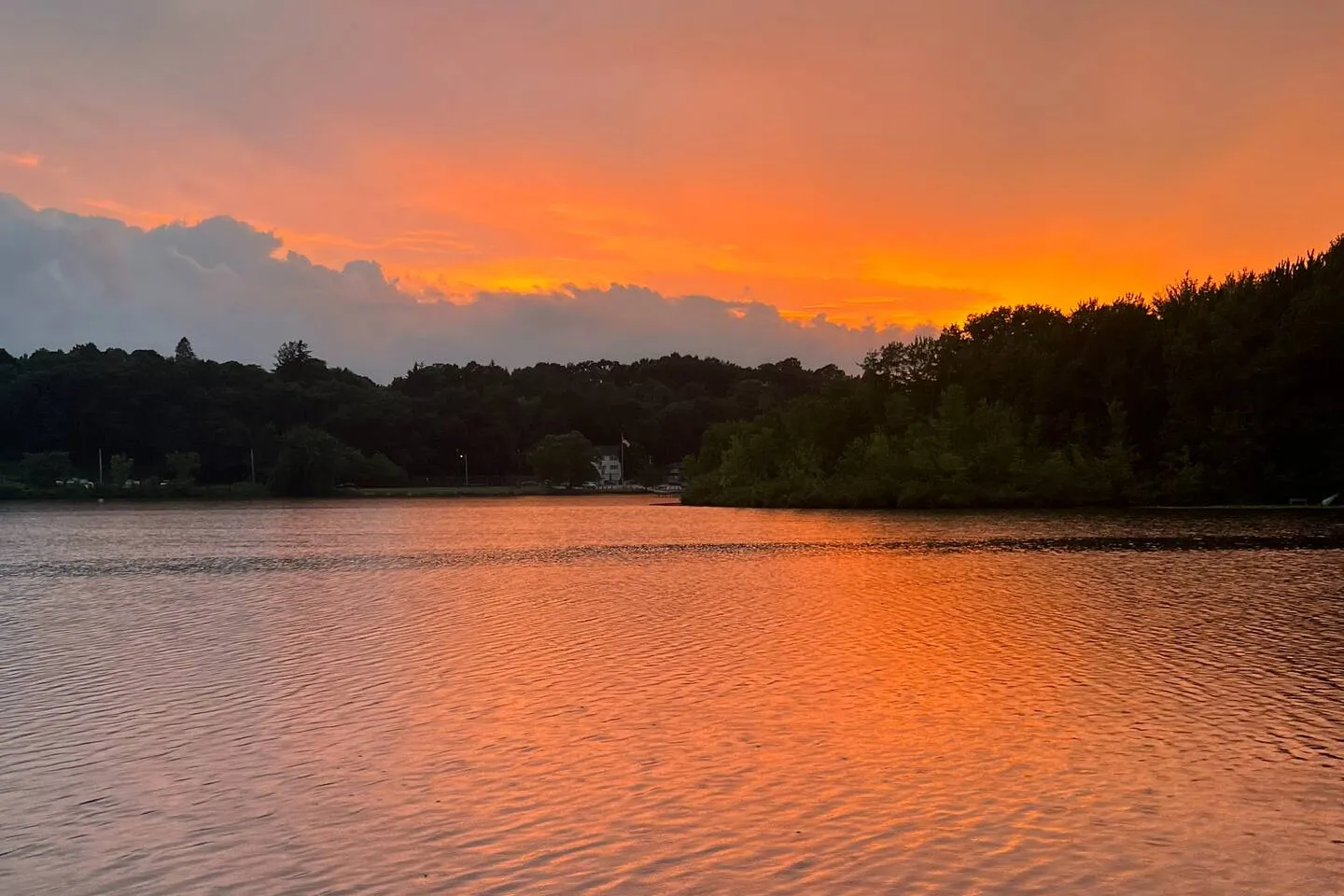 Sunset over Indian Lake in Worcester: an orange sky reflected in the water, with the tree line of the far shore dark against it.